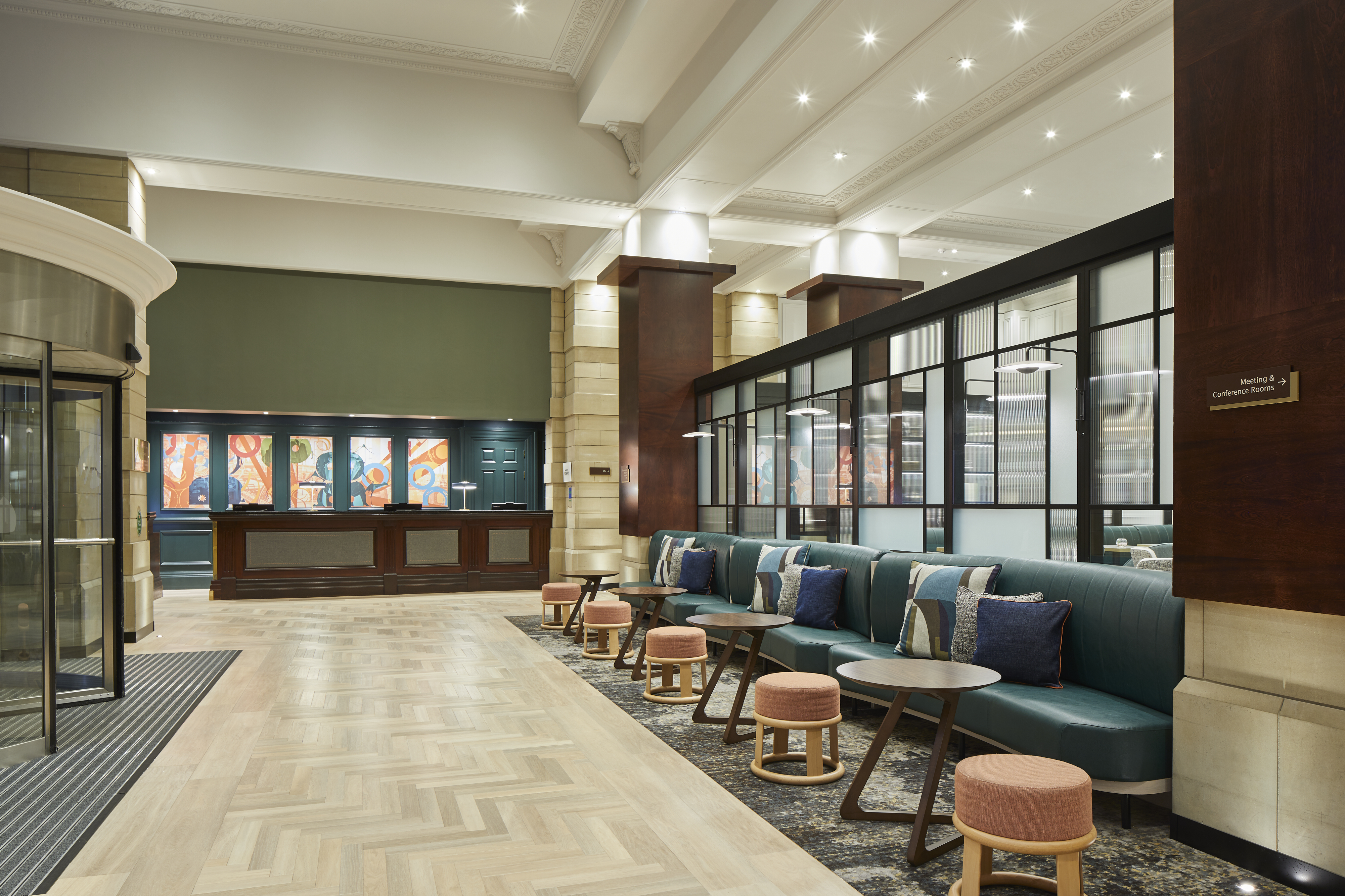 Lobby with upholstered bench seating along the windows, with throw pillows and small round tables