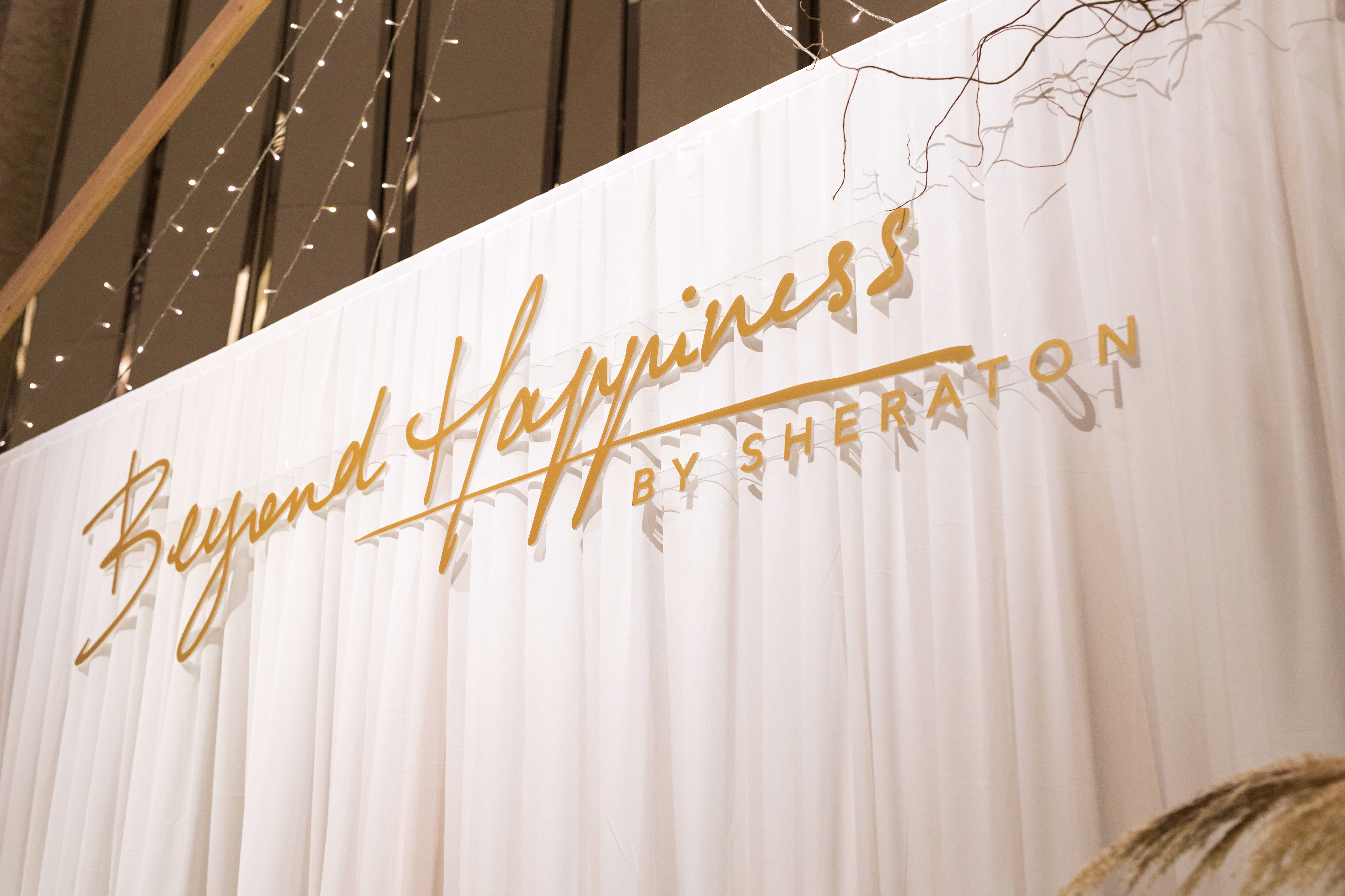 White curtain with Beyond Happiness by Sheraton written in gold letters