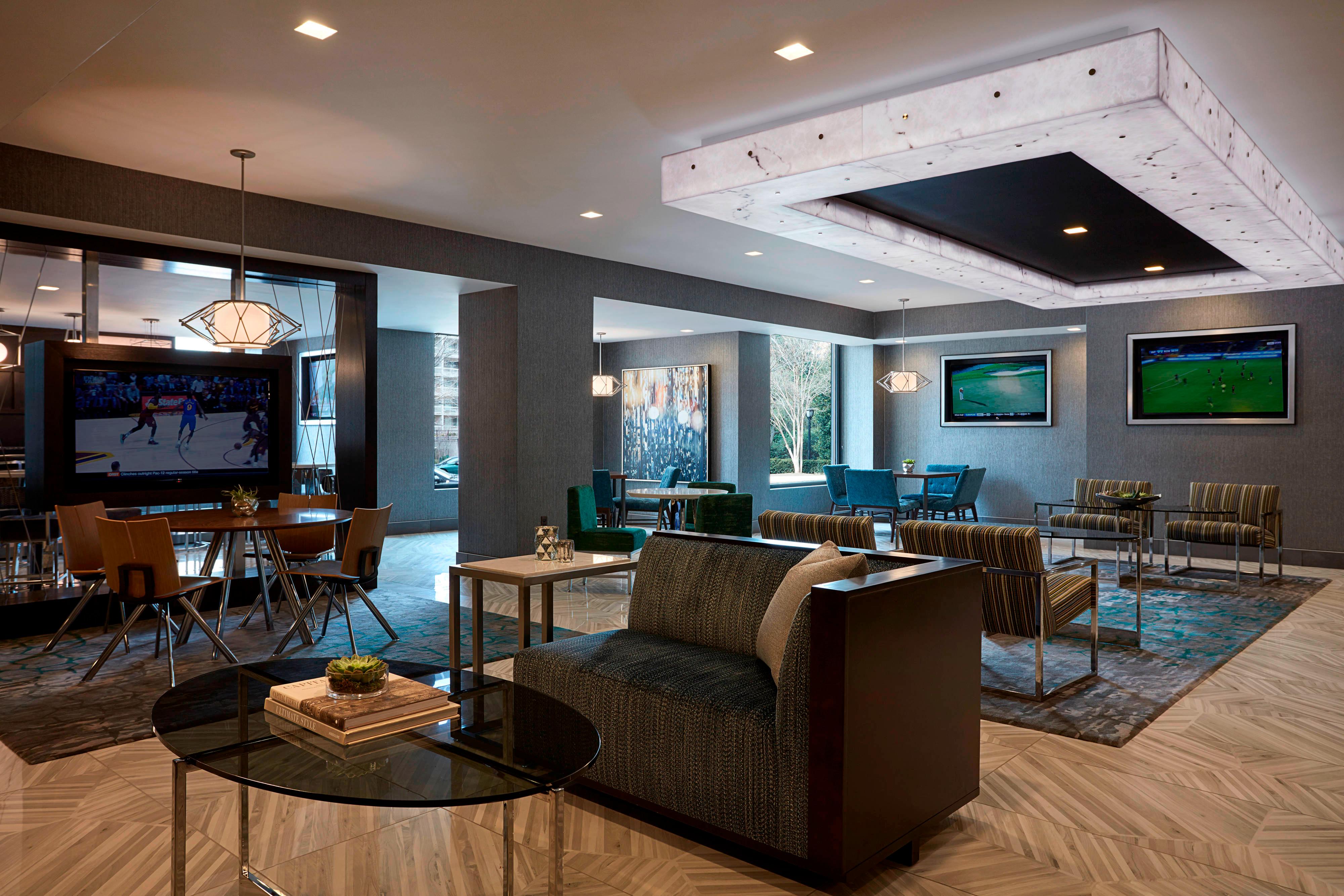 Lounge area with upholstered chairs and flatscreen TVs on walls