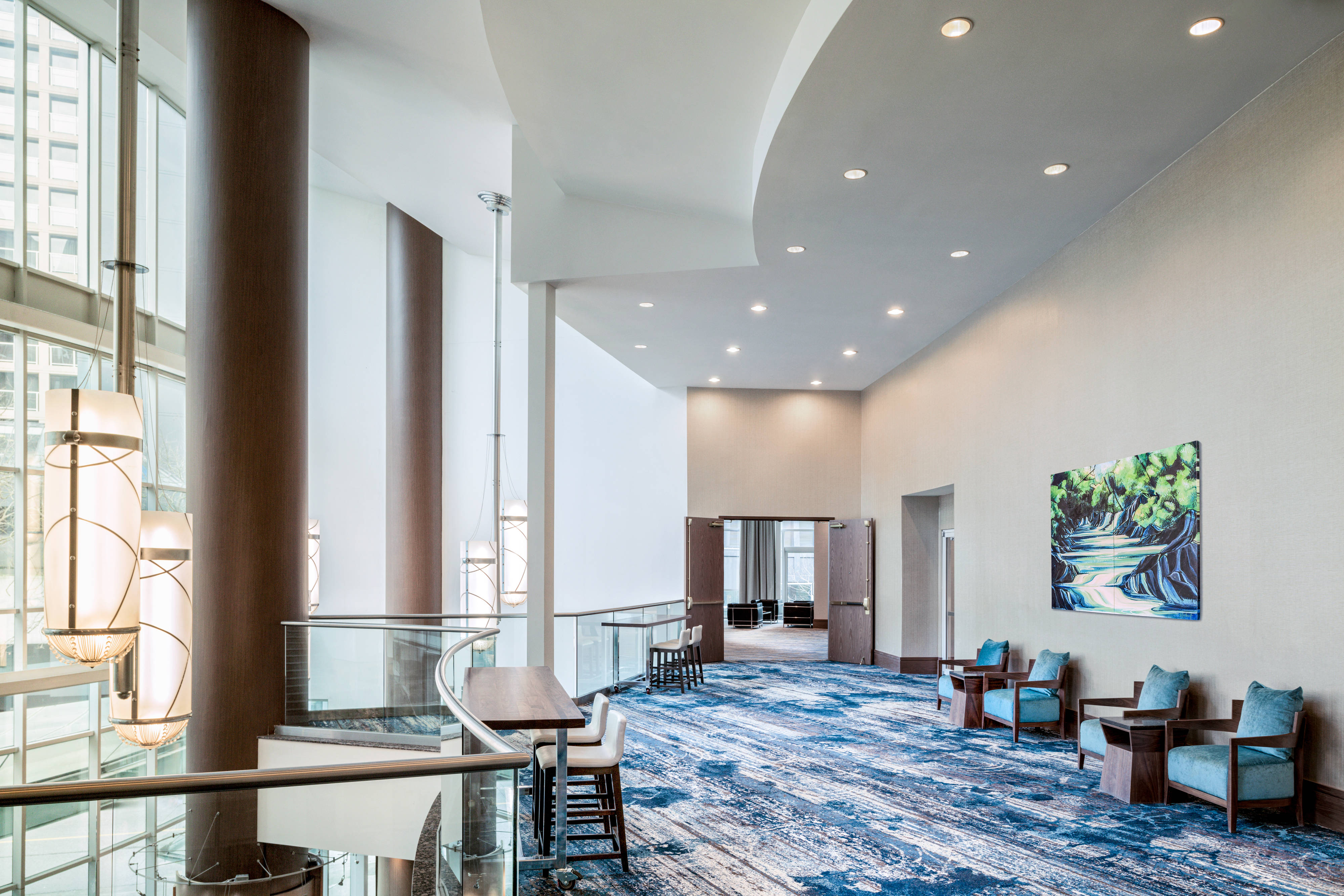 A brightly-lit open lobby space with table seating and padded chairs.