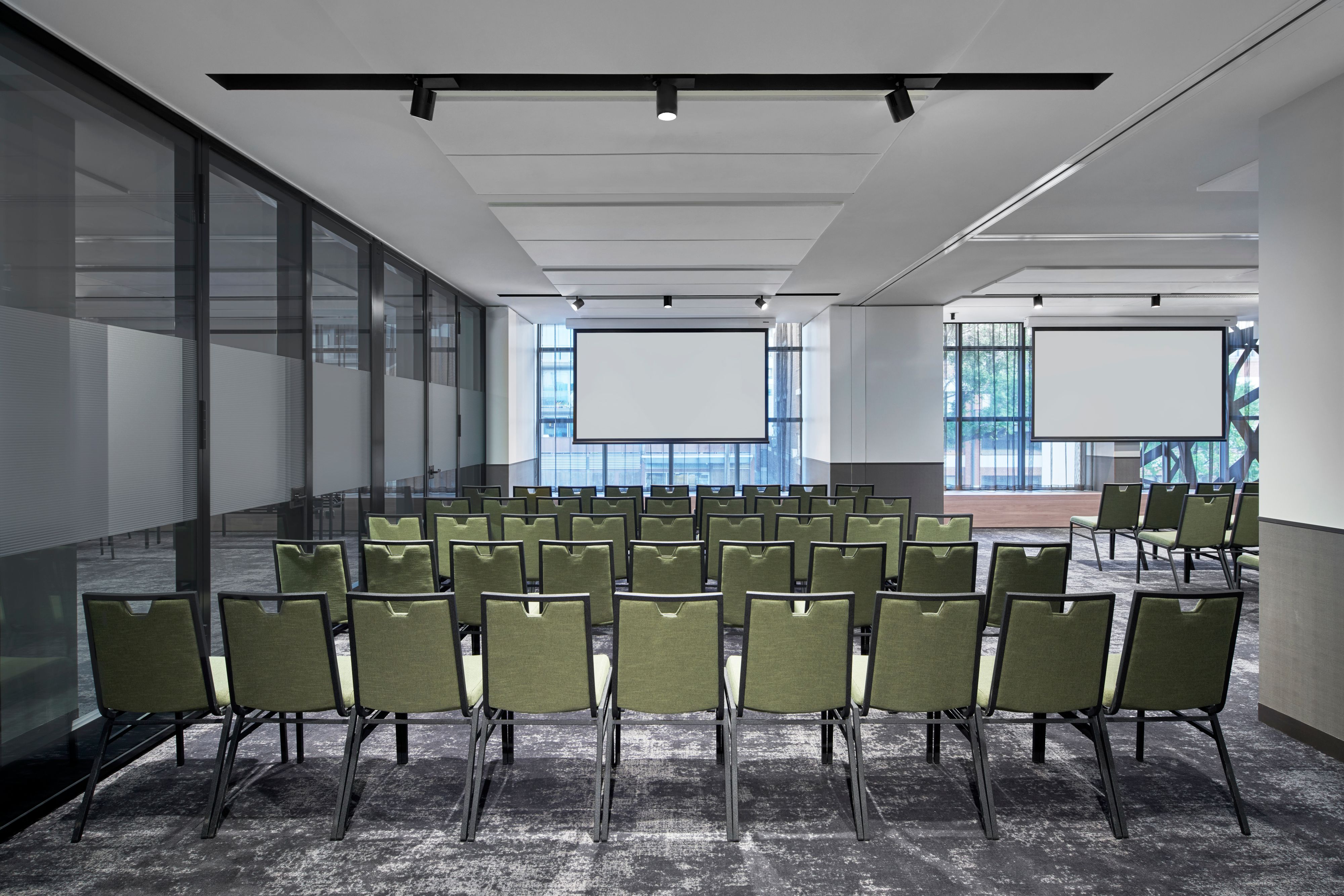 Meeting room setup with rows of chairs and projector screens