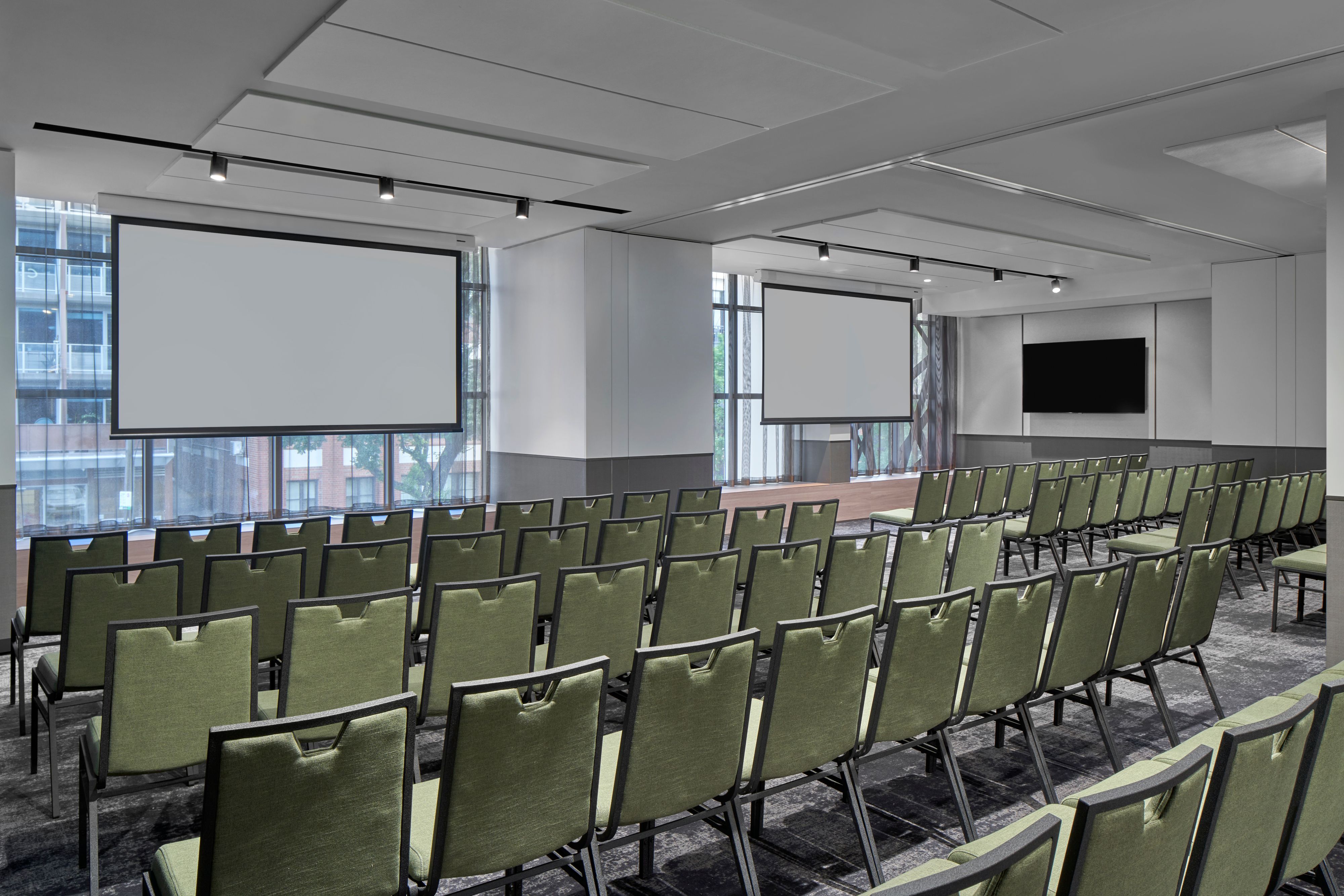 Large meeting room with rows of chairs and projector screens